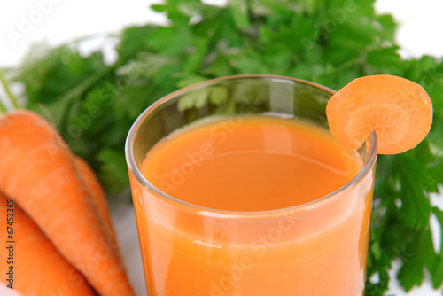 Glass of carrot juice with fresh carrots and parsley close up