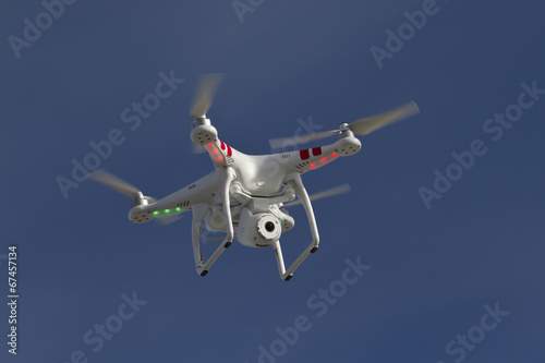 small unmanned helicopter with a camera floating in the blue sky