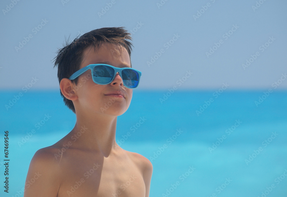 Portrait of young boy wearing sunglasses and posing by sea Portrait of young boy wearing sunglasses and posing by sea