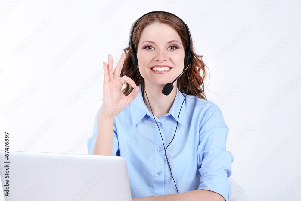 Young woman with headset sitting at table with notebook in room Young woman with headset sitting at table with notebook in room
