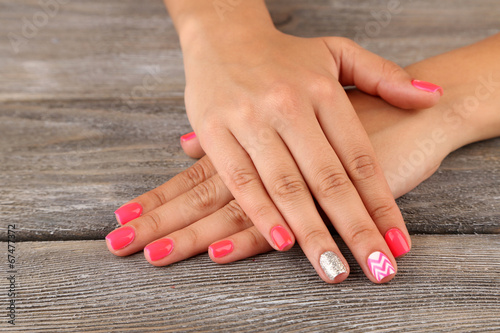 Female hand with stylish colorful nails  on wooden background