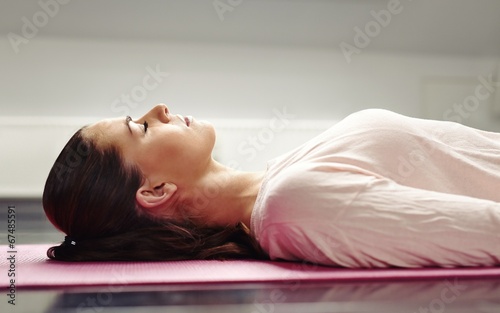 Woman lying on yoga mat relaxing her muscles photo