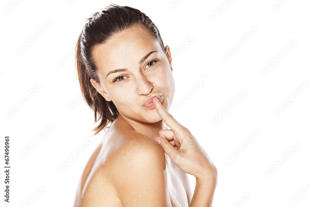 young girl without make up, and pursed lips, kissing her finger young girl without make up, and pursed lips, kissing her finger
