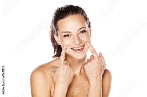 young beautiful girl forcing a smile with her fingers photo