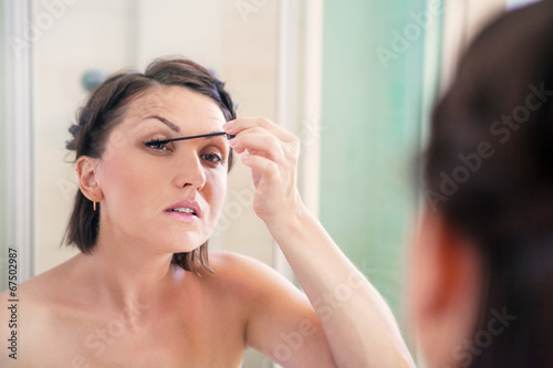 Woman makes light day makeup in bathroom