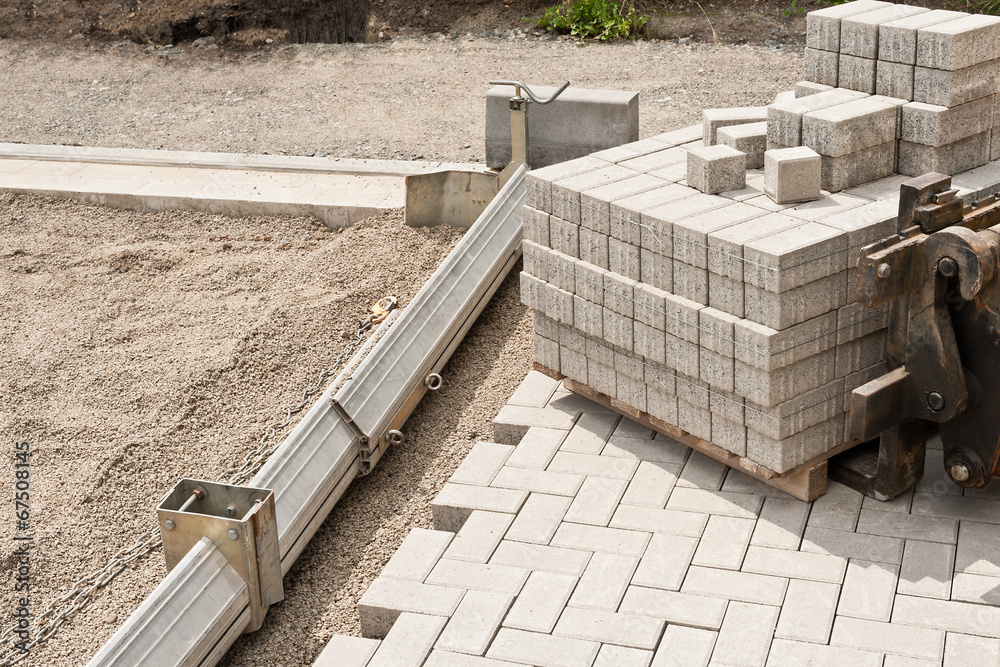Neue Pflastersteine aus Beton werden in einem Kiesbett verlegt Neue Pflastersteine aus Beton werden in einem Kiesbett verlegt