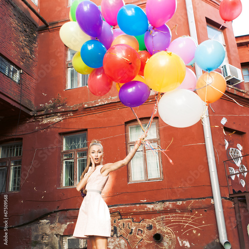 beautiful lady in retro outfit holding a bunch of balloons betwe photo