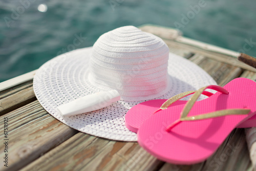 close up of hat, sunscreen and slippers at seaside