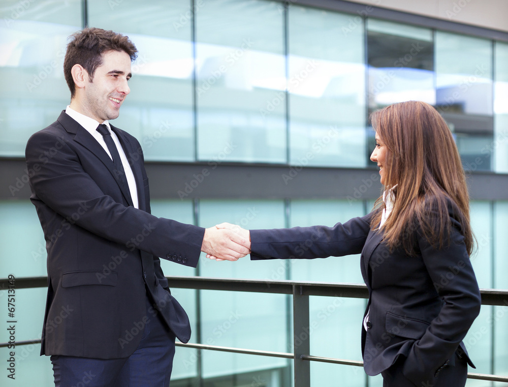 Business partners shaking hands in meeting hall Business partners shaking hands in meeting hall
