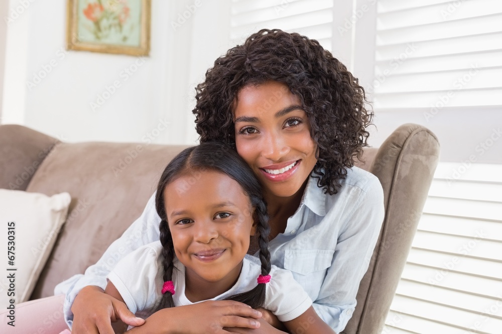 Pretty mother sitting on the couch with her daughter smiling at Pretty mother sitting on the couch with her daughter smiling at