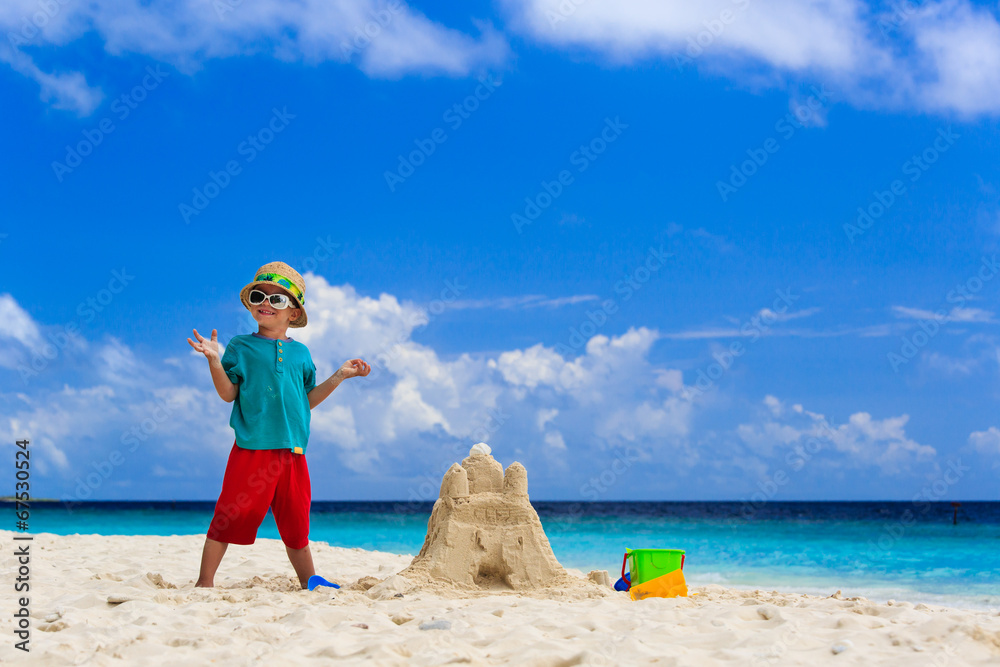 happy child with built sand castle on the beach