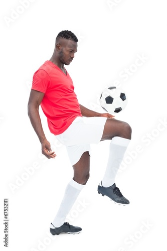 Fototapeta Naklejka Na Ścianę i Meble -  Football player in red jersey controlling ball