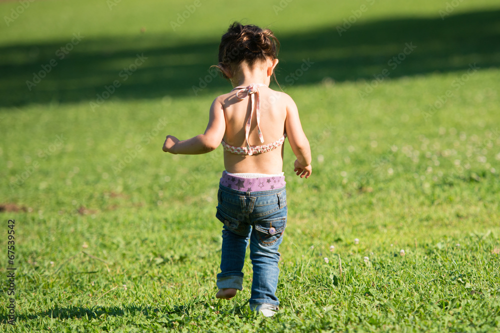 Happy little toddler girl walking on the green grass Happy little toddler girl walking on the green grass