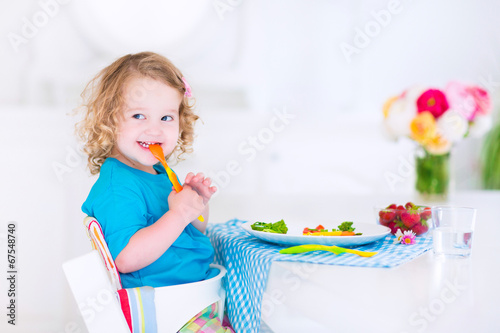 Little funny girl eating salad for lunch