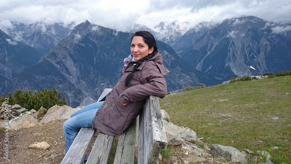 Naklejka premium Junge Frau auf Bank in bergpanorama