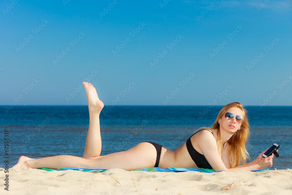 Summer vacation Girl with phone tanning on beach Summer vacation Girl with phone tanning on beach