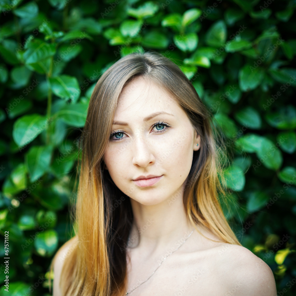 Close up portrait of young woman with natural green hedge backgr Close up portrait of young woman with natural green hedge backgr