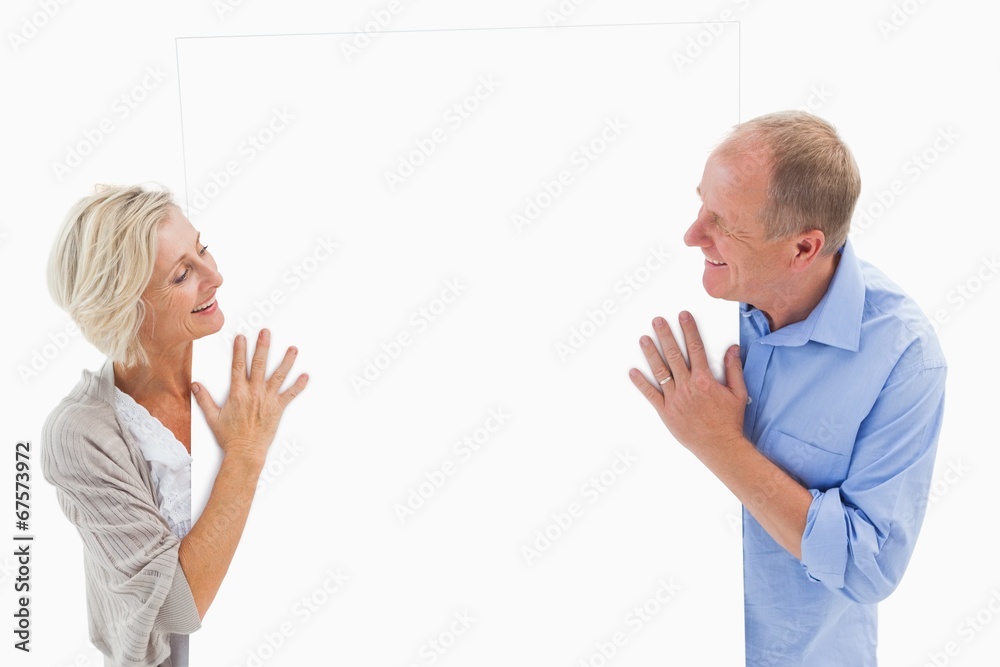 Mature couple smiling and holding card Mature couple smiling and holding card