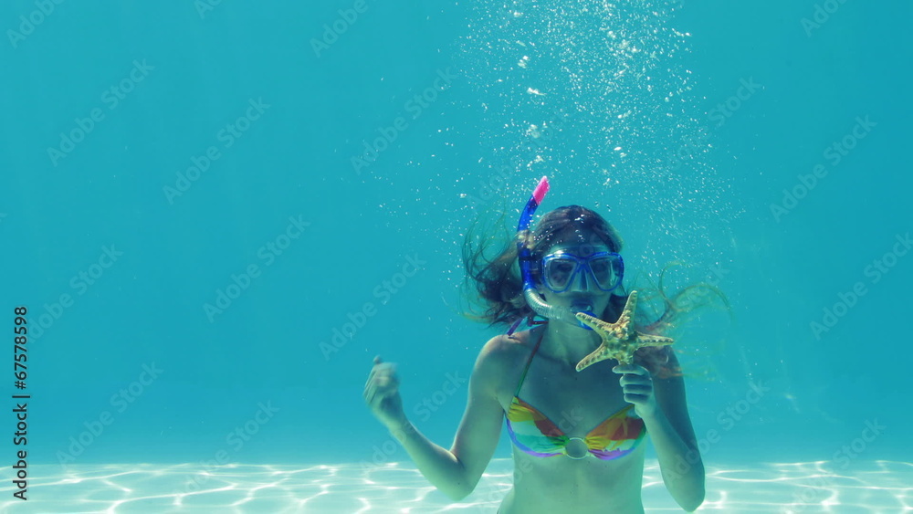 Happy blonde jumping into swimming pool wearing snorkel and hold