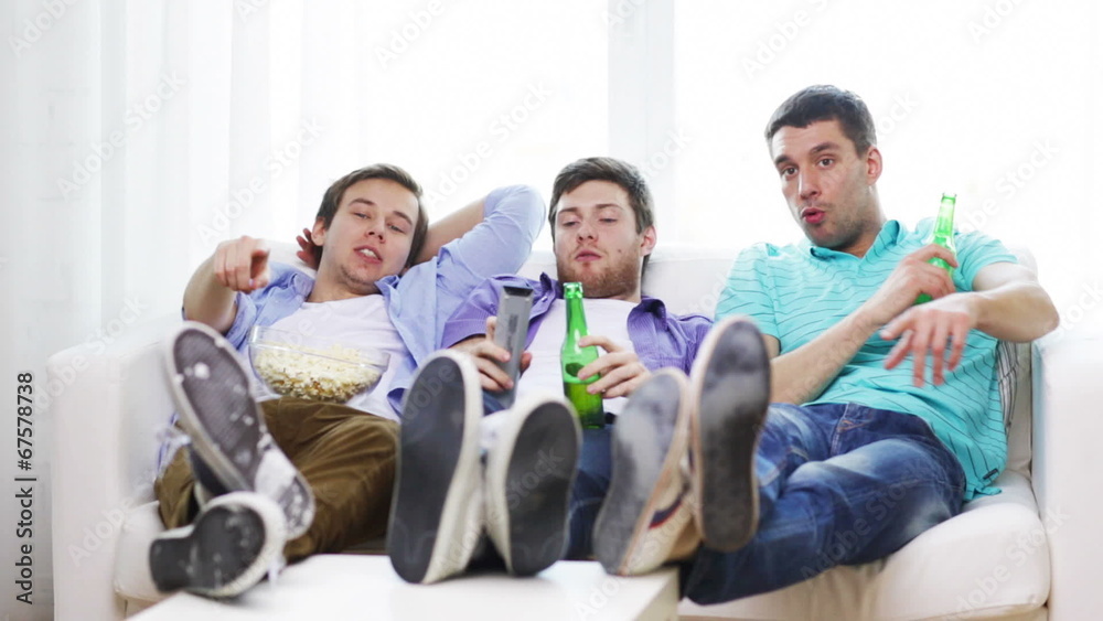 male friends with beer watching tv at home