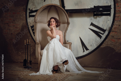 A smiling girl in a wedding dress in strange chair.  photo