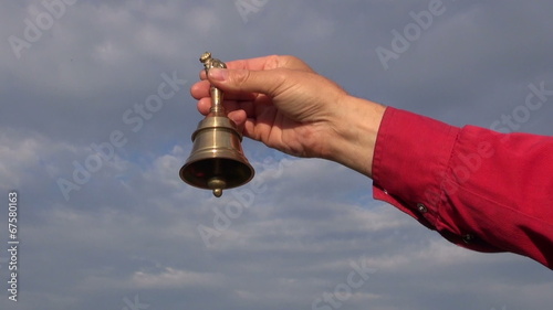 hand hold ornamental  brass jingle bell on blue sky background