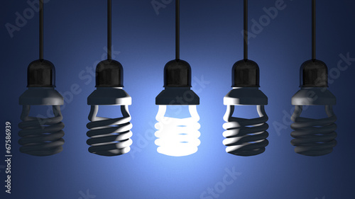 Glowing spiral Light bulb hanging among dead ones