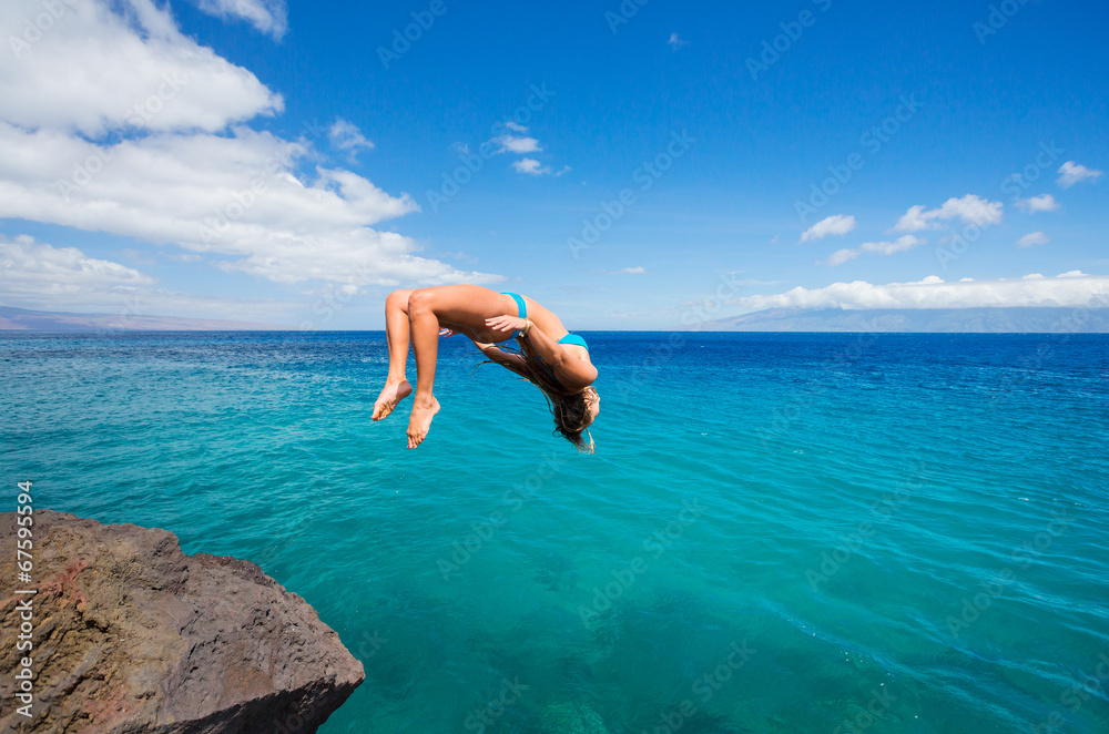 Woman doing backflip into ocean Woman doing backflip into ocean