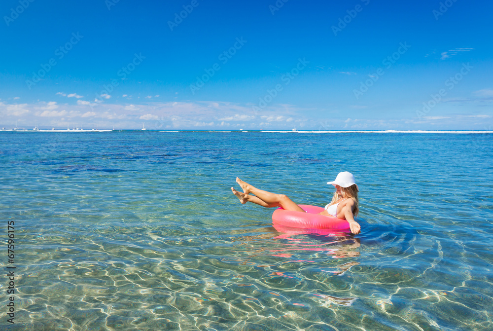 Woman floating on raft in tropical ocean