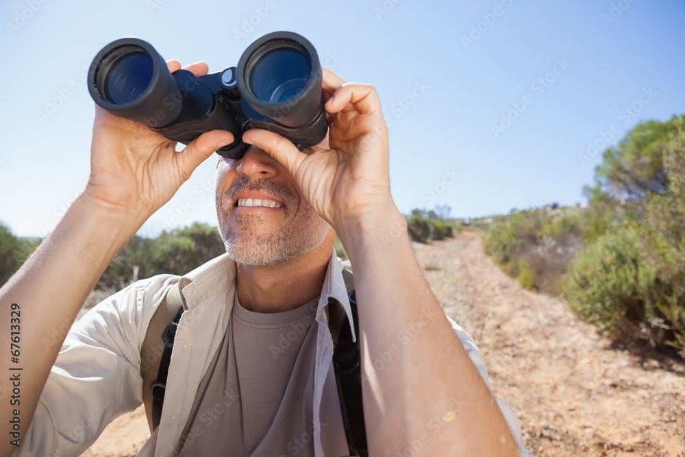 Hiker looking through his binoculars on country trail Hiker looking through his binoculars on country trail