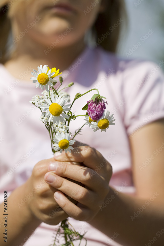 Young girl holding daisy flowers outdoors