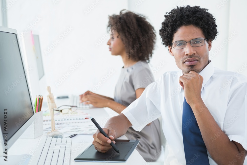 Young designer looking at camera at his desk Young designer looking at camera at his desk