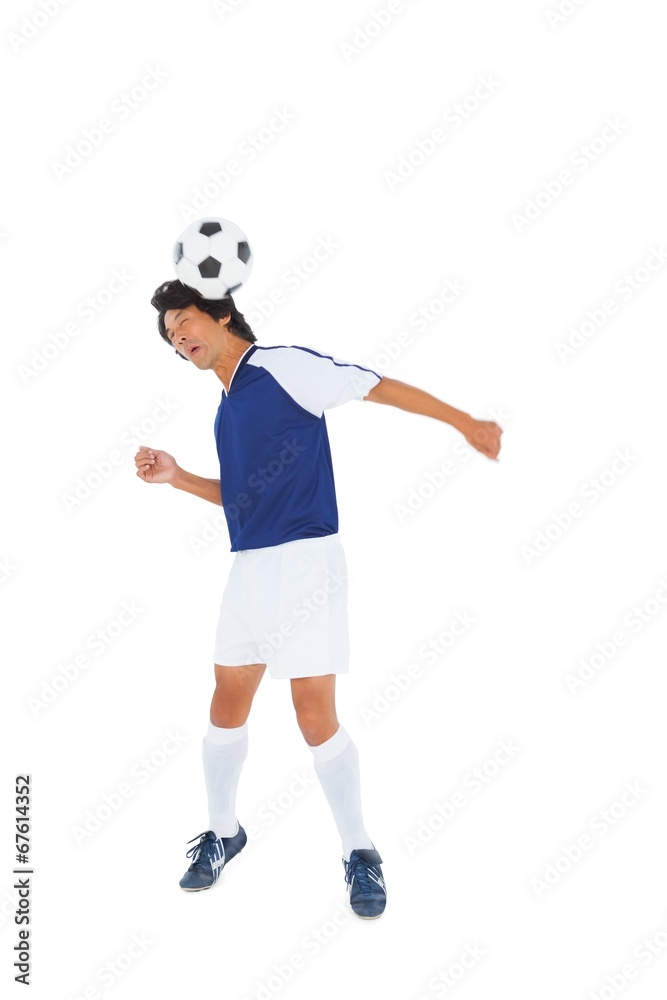 Football player in blue heading the ball