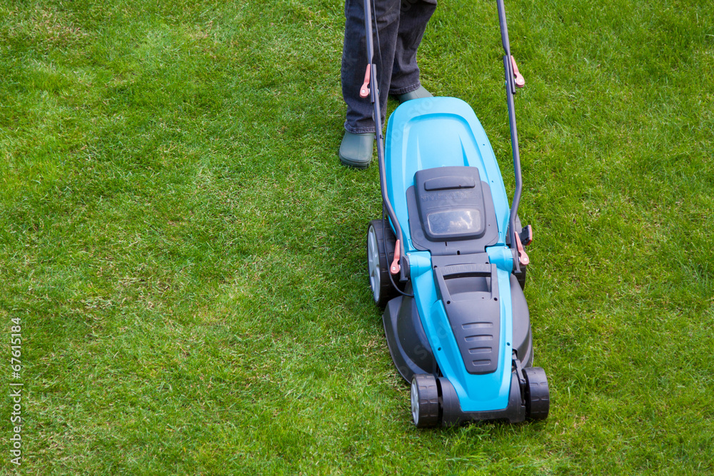 man with an electric mower on green grass