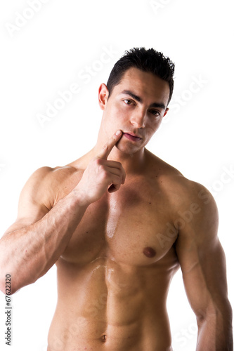 Muscular shirtless young man touching lips with finger