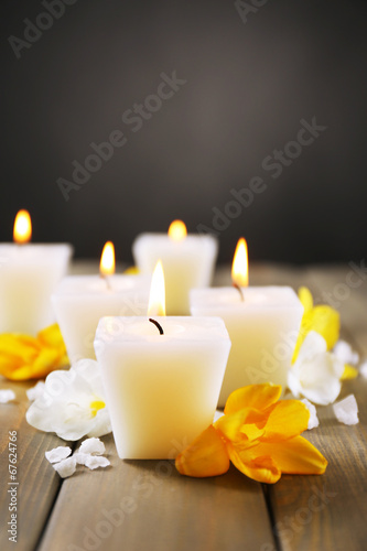 Beautiful candles with flowers on wooden background