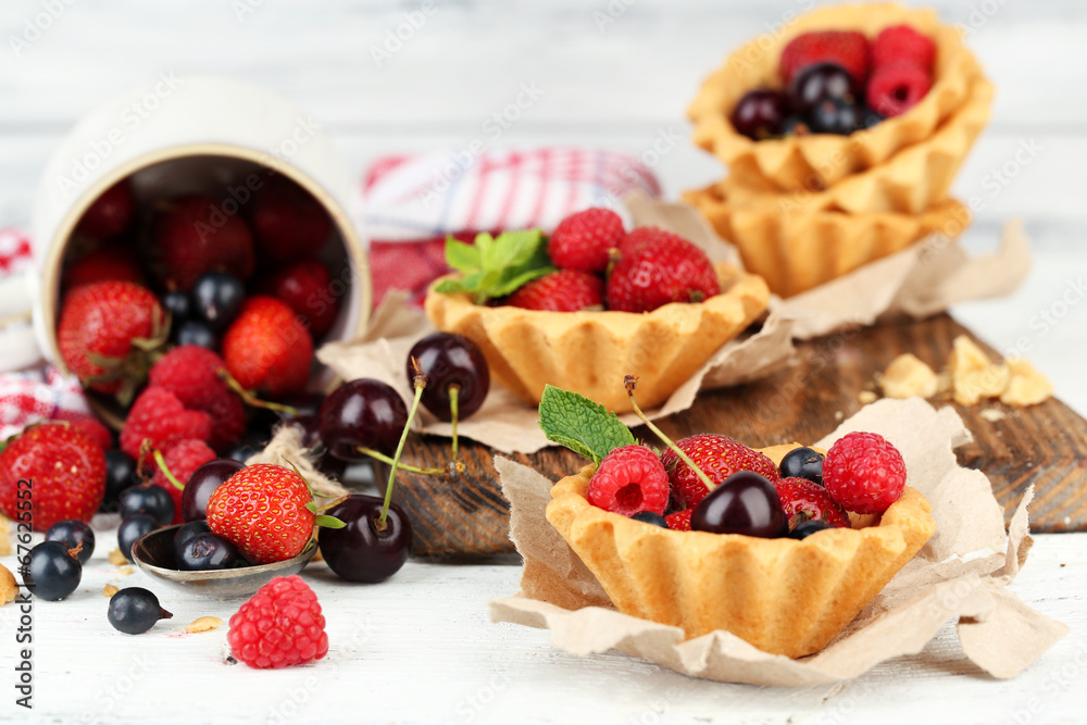 Tasty tartlets with berries on wooden table Tasty tartlets with berries on wooden table