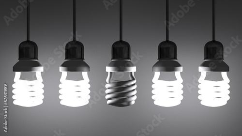 Dead spiral light bulb hanging among glowing ones