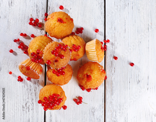 Tasty muffin with red currant berries on color wooden