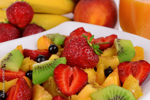 Fresh fruits salad on plate with berries and juice close up