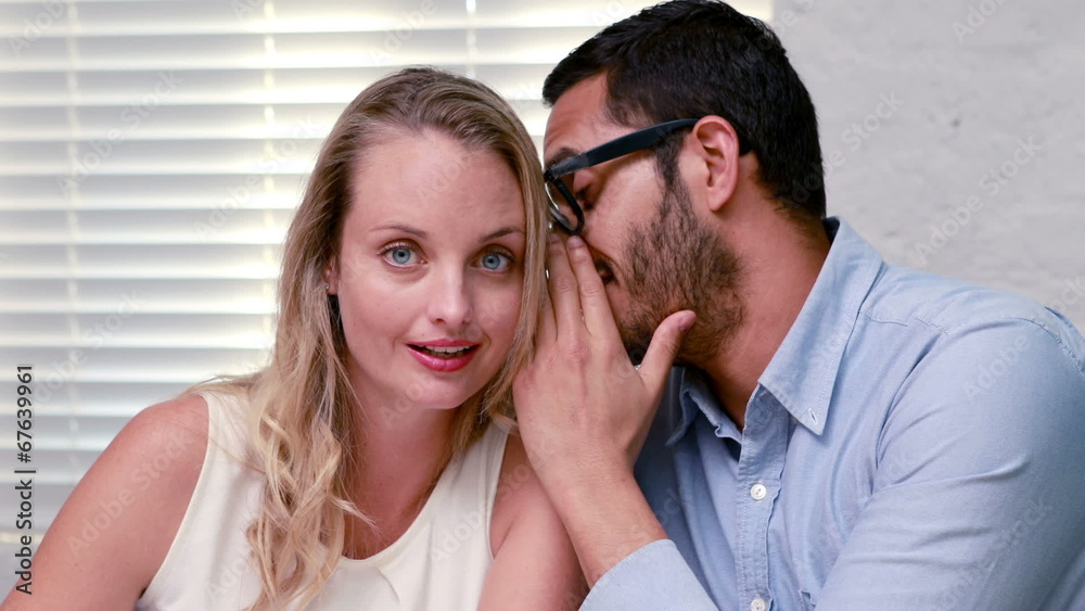Casual businessman whispering a secret to colleague Casual businessman whispering a secret to colleague
