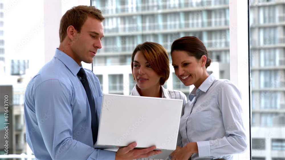 Business team standing and working on laptop together Business team standing and working on laptop together
