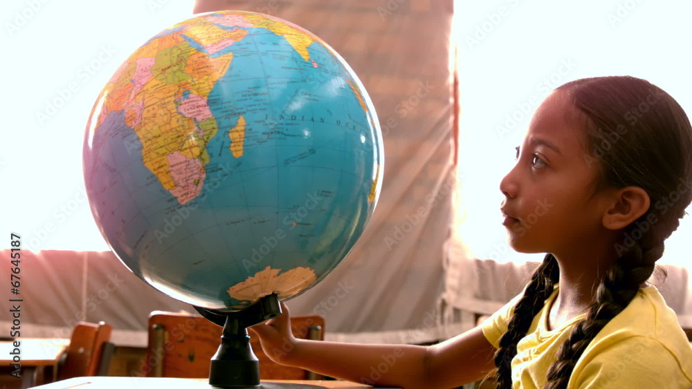 Little girl looking at globe in classroom