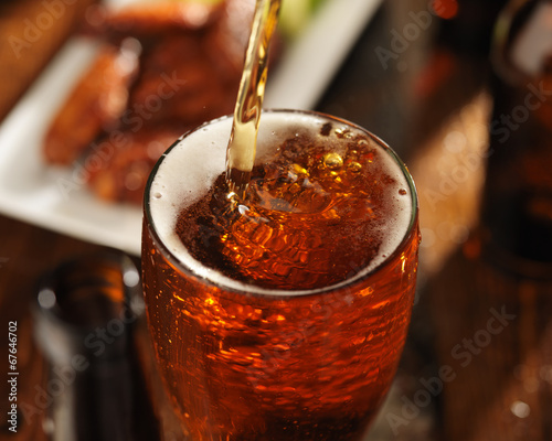 pouring beer into glass with bbq chicken wings in background 02