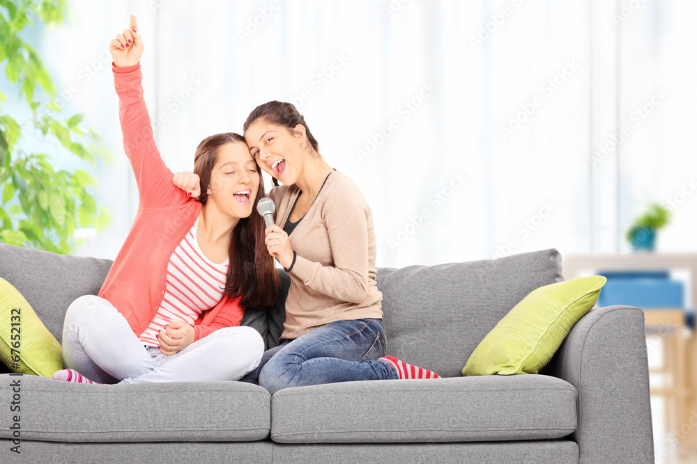 Fototapeta premium Two sisters having fun singing on microphone