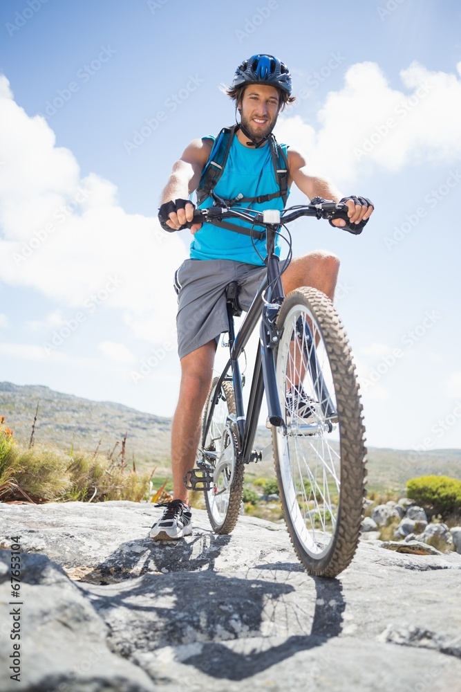 Fototapeta premium Fit man cycling on rocky terrain