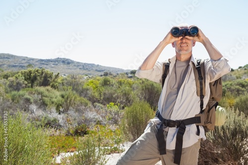 Hiker looking through binoculars on country trail