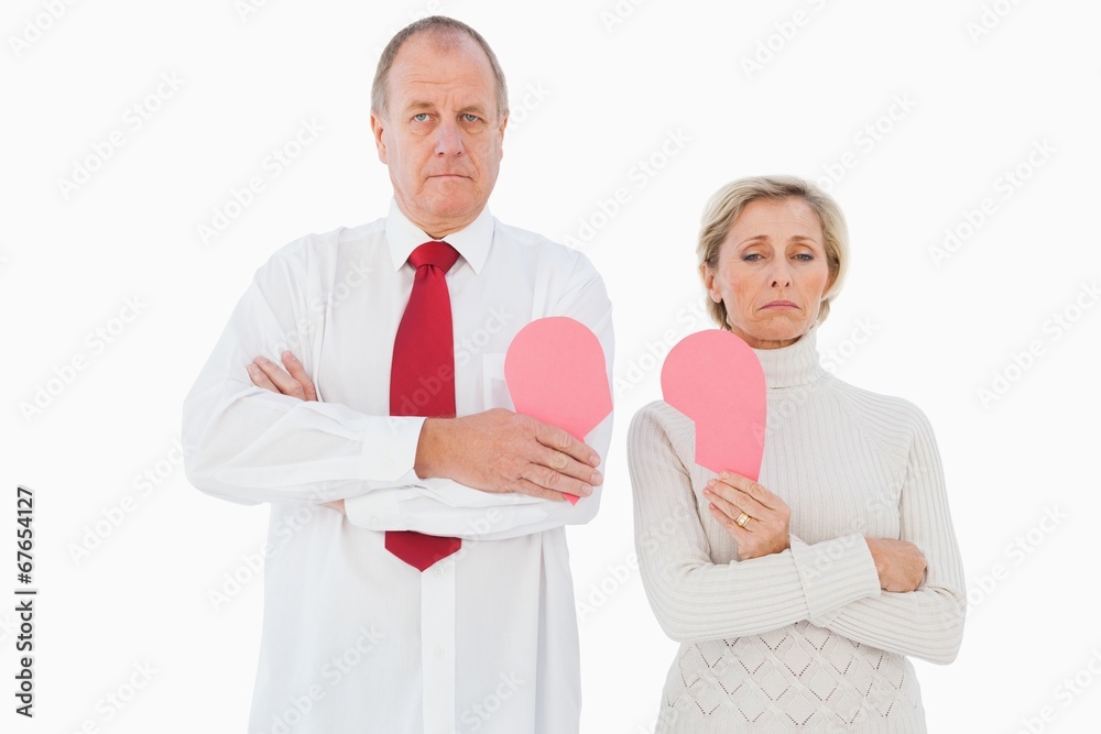 Older couple standing holding broken pink heart Older couple standing holding broken pink heart