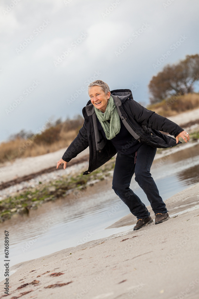 Happy senior woman frolicking on the beach Happy senior woman frolicking on the beach