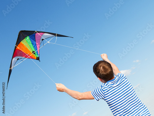 boy flies kite into blue sky